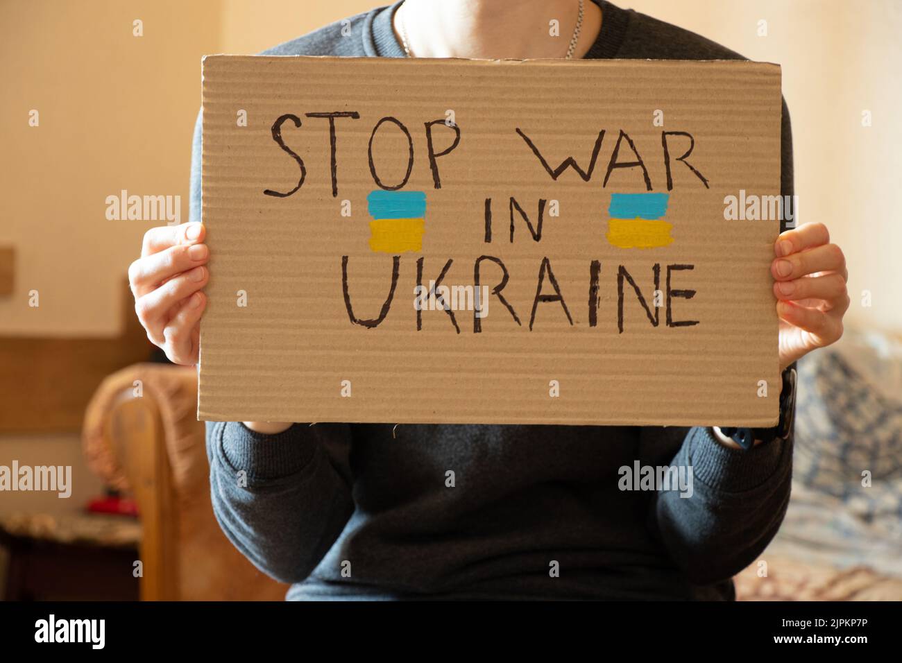 Stoppen Sie den Krieg in der Ukraine geschrieben auf einem Zeichen, dass eine Frau in ihren Händen hält aus ihrem Haus in der Dnepr, Protestaktion, Kriegsrecht in der Ukraine 2022 Stockfoto