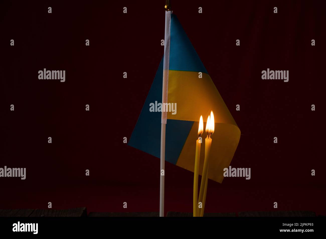 Drei Kerzen auf dem Hintergrund der Nationalflagge der Ukraine im Dunkeln zu Hause, stoppen den Krieg in der Ukraine, ein Gebet für das Land Stockfoto