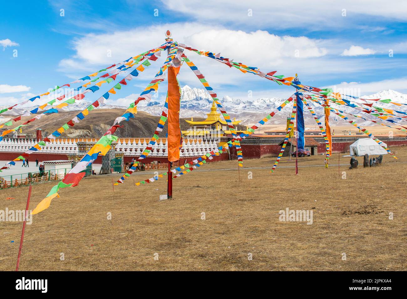 Tibetisch-buddhistisches Kloster in Tagong hingen farbenfrohe tibetisch-buddhistische Gebetsfahnen an einem Pfahl und der verschneite Berg 'Yala' im Hintergrund. Stockfoto