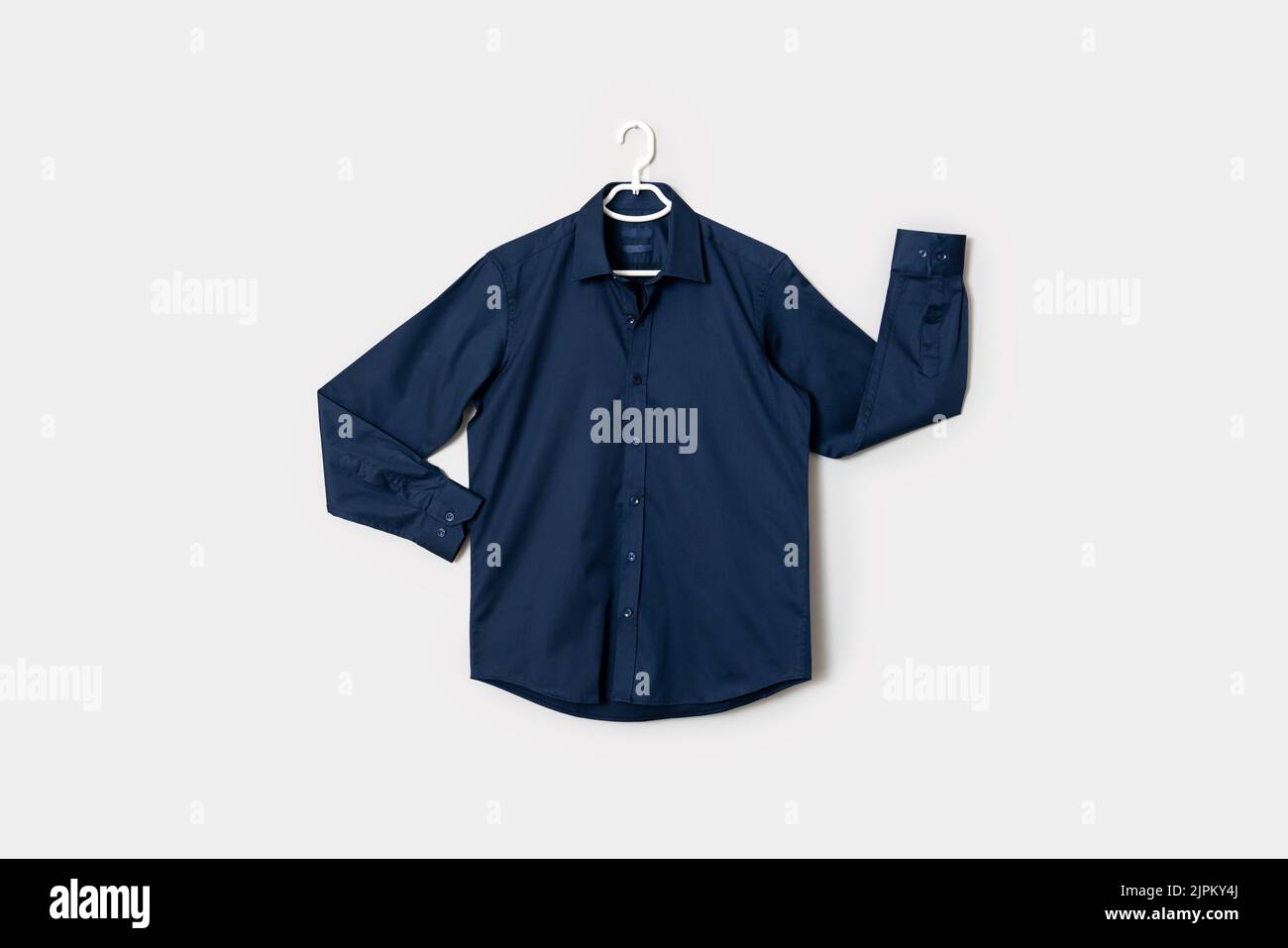 Die Vorderansicht eines dunkelblauen Button-Down-Shirts auf einem Hemdaufhänger, isoliert auf weißem Hintergrund. Hochwertige Fotos Stockfoto