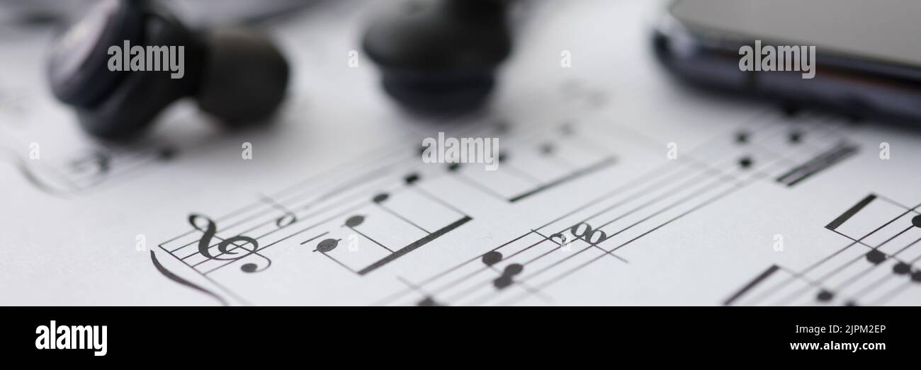 Musiknoten Kopfhörer Smartphone auf Tisch Nahaufnahme Stockfoto