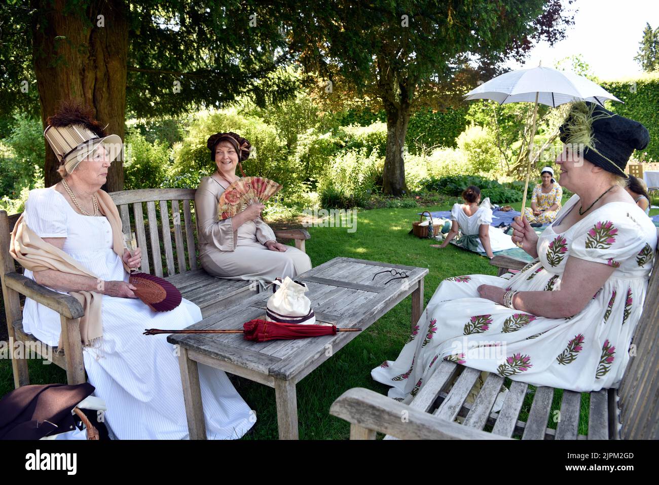 Frauen in Regency-Ära (1811-20) Kostüm sitzen im Garten von Jane Austen’s House, Chawton, in der Nähe von Alton, Hampshire, Großbritannien. Stockfoto