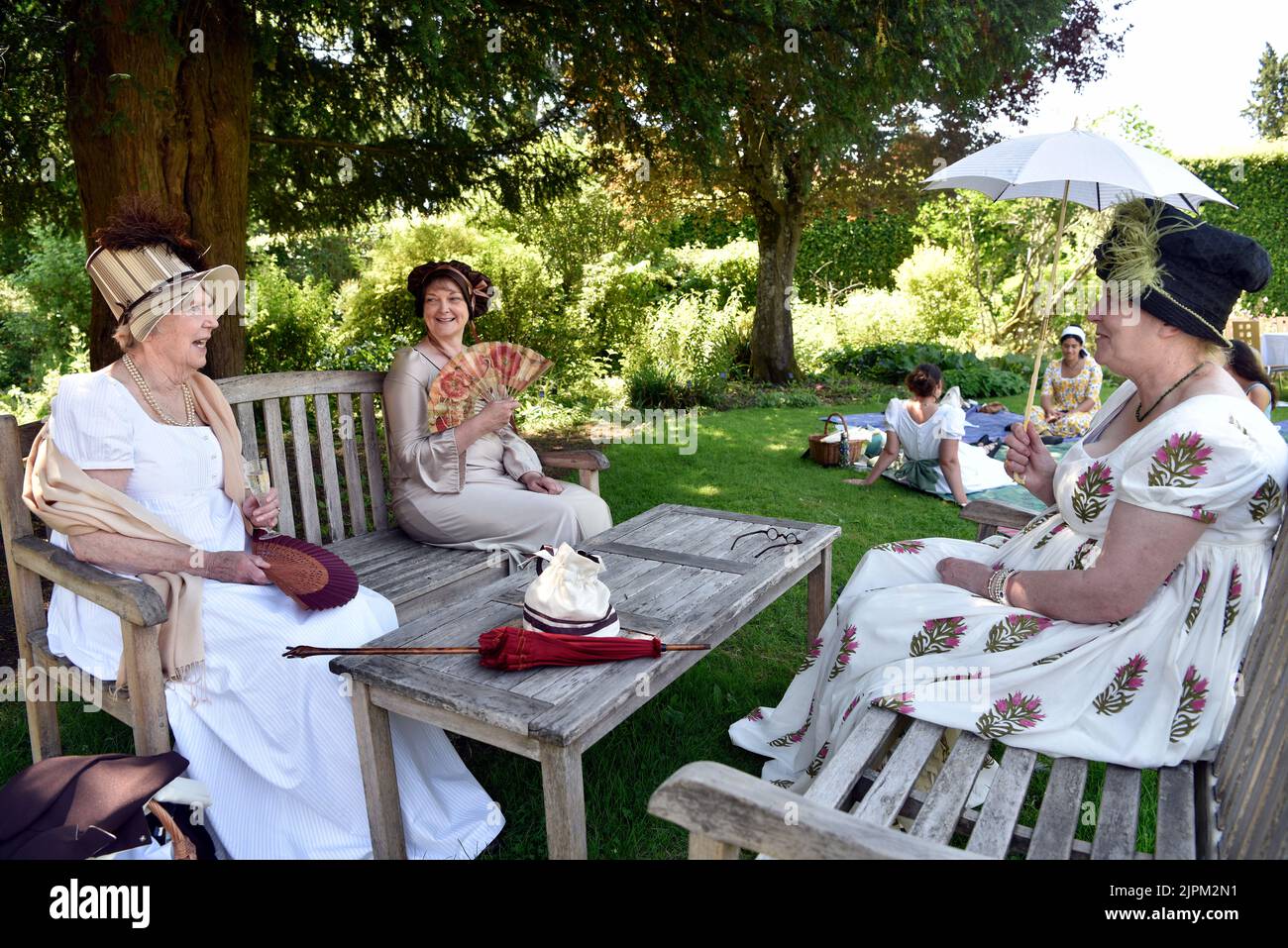 Frauen in Regency-Ära (1811-20) Kostüm sitzen im Garten von Jane Austen’s House, Chawton, in der Nähe von Alton, Hampshire, Großbritannien. Stockfoto