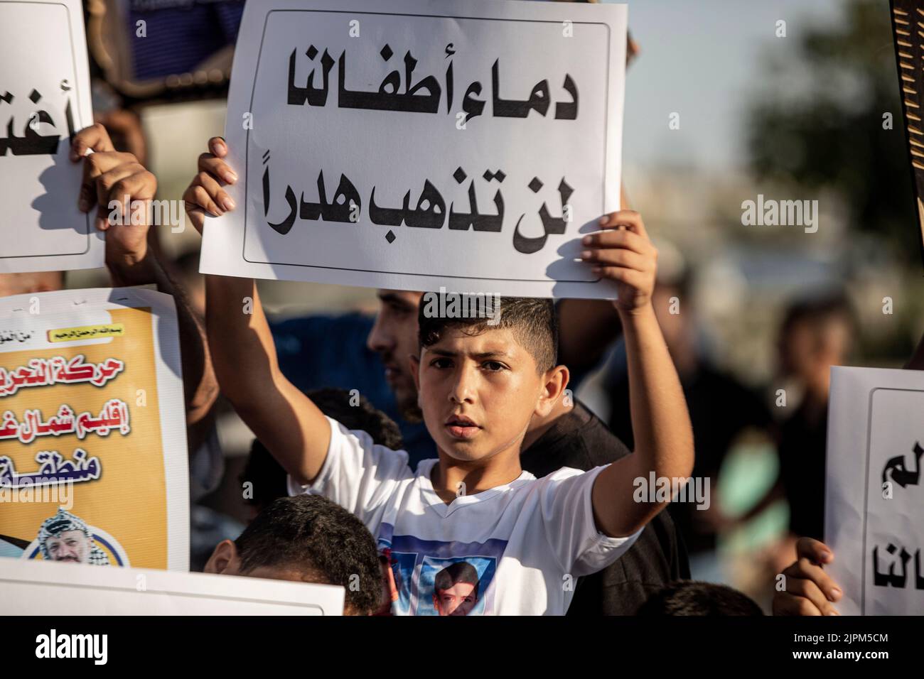 Gazastreifen, Palästinensische Gebiete. 19.. August 2022. Palästinensische Kinder halten Bilder von Kindern, die während der jüngsten Kämpfe zwischen Israel und Gaza während einer Mahnwache in der Nähe ihrer Gräber in Jabalia im nördlichen Gazastreifen getötet wurden, Israel hat die Verantwortung für die Tötung von fünf palästinensischen Kindern bei einem israelischen Luftangriff auf den Friedhof von Falludscha in der Stadt Jabalia im nördlichen Gazastreifen übernommen. Stockfoto