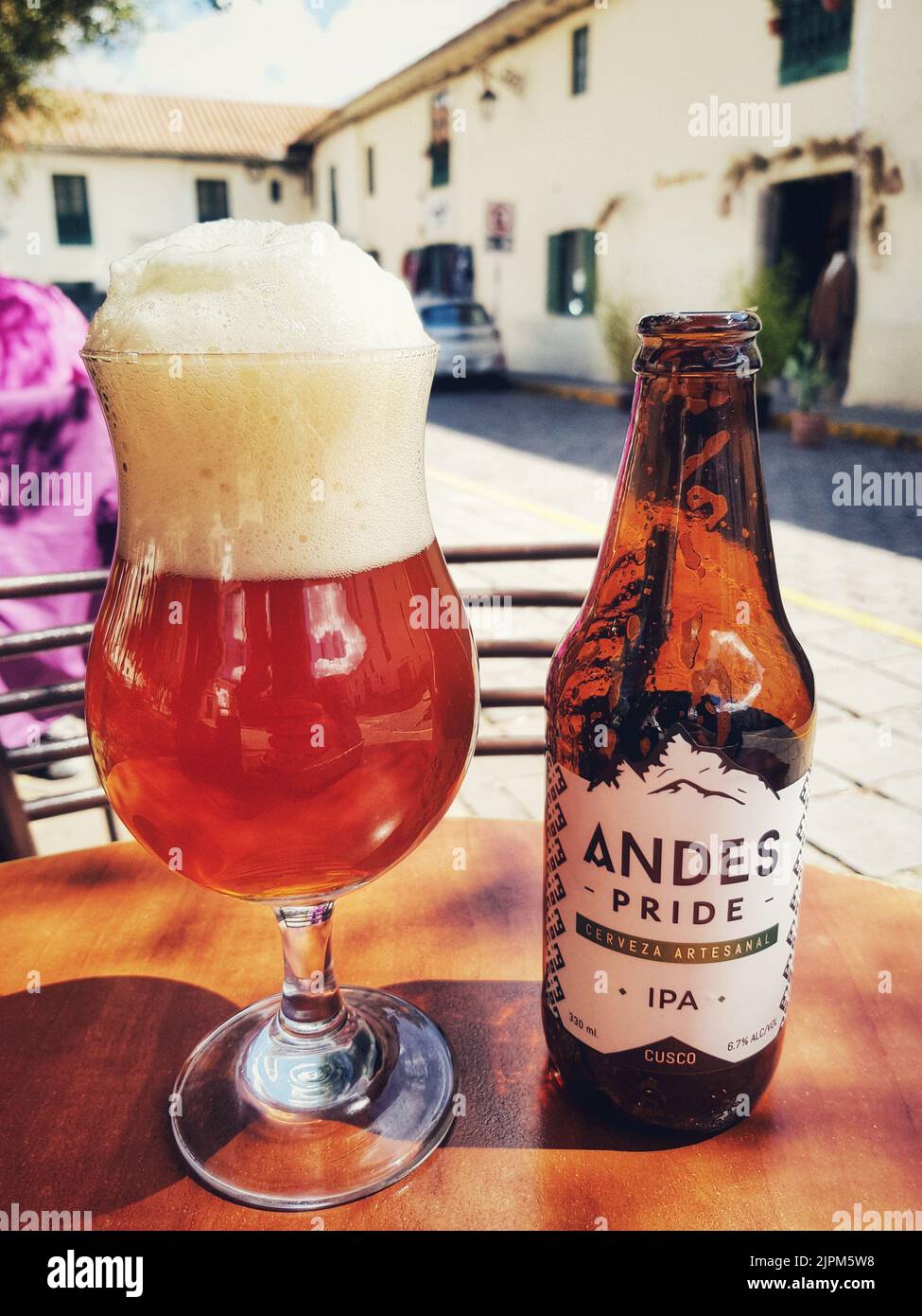 Eine leere Flasche Andes IPA-Bier mit einem vollen Glas Bier daneben, vertikaler Schuss Stockfoto