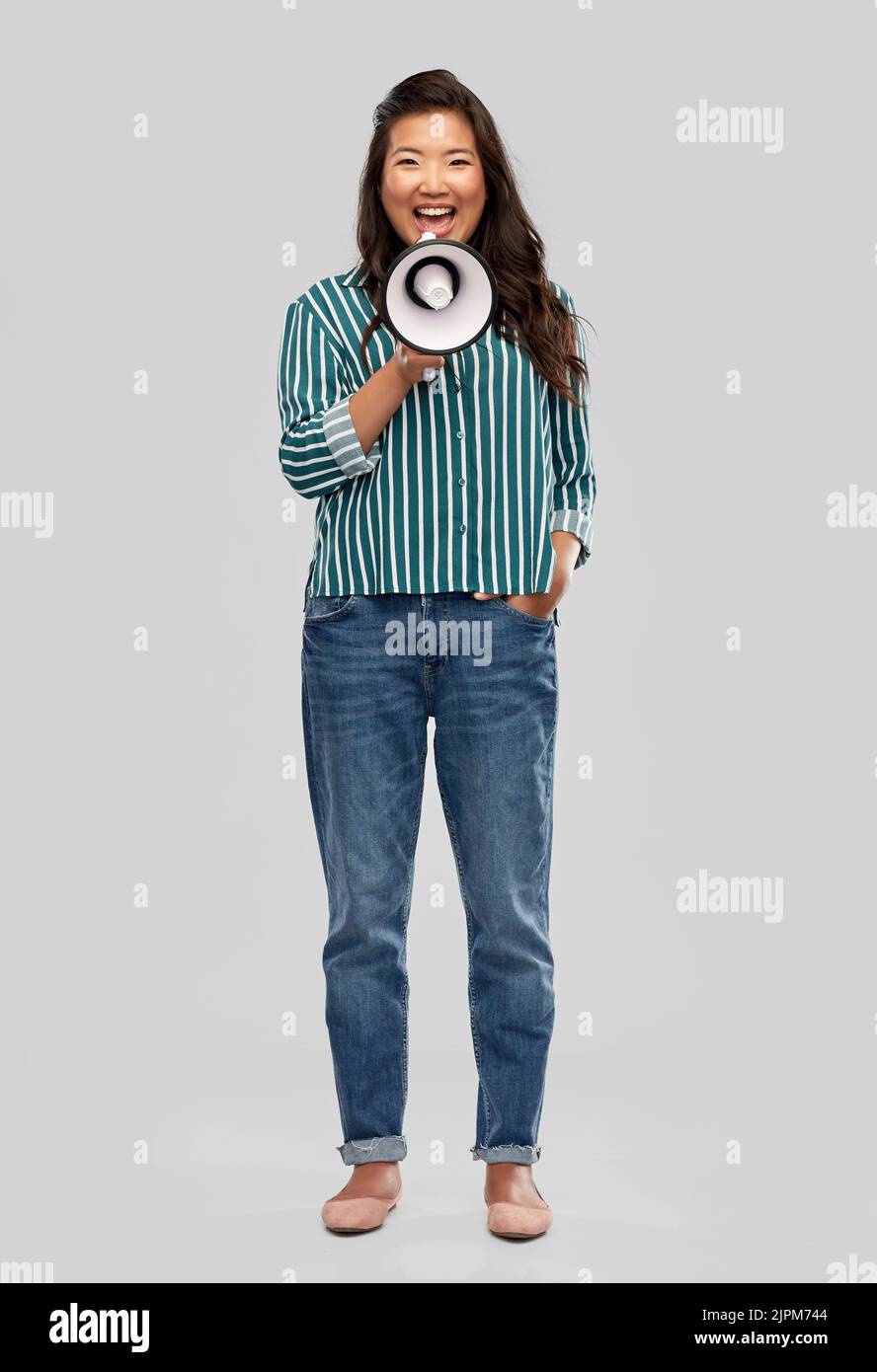 Glücklich lächelnde asiatische Frau, die mit Megaphon spricht Stockfoto
