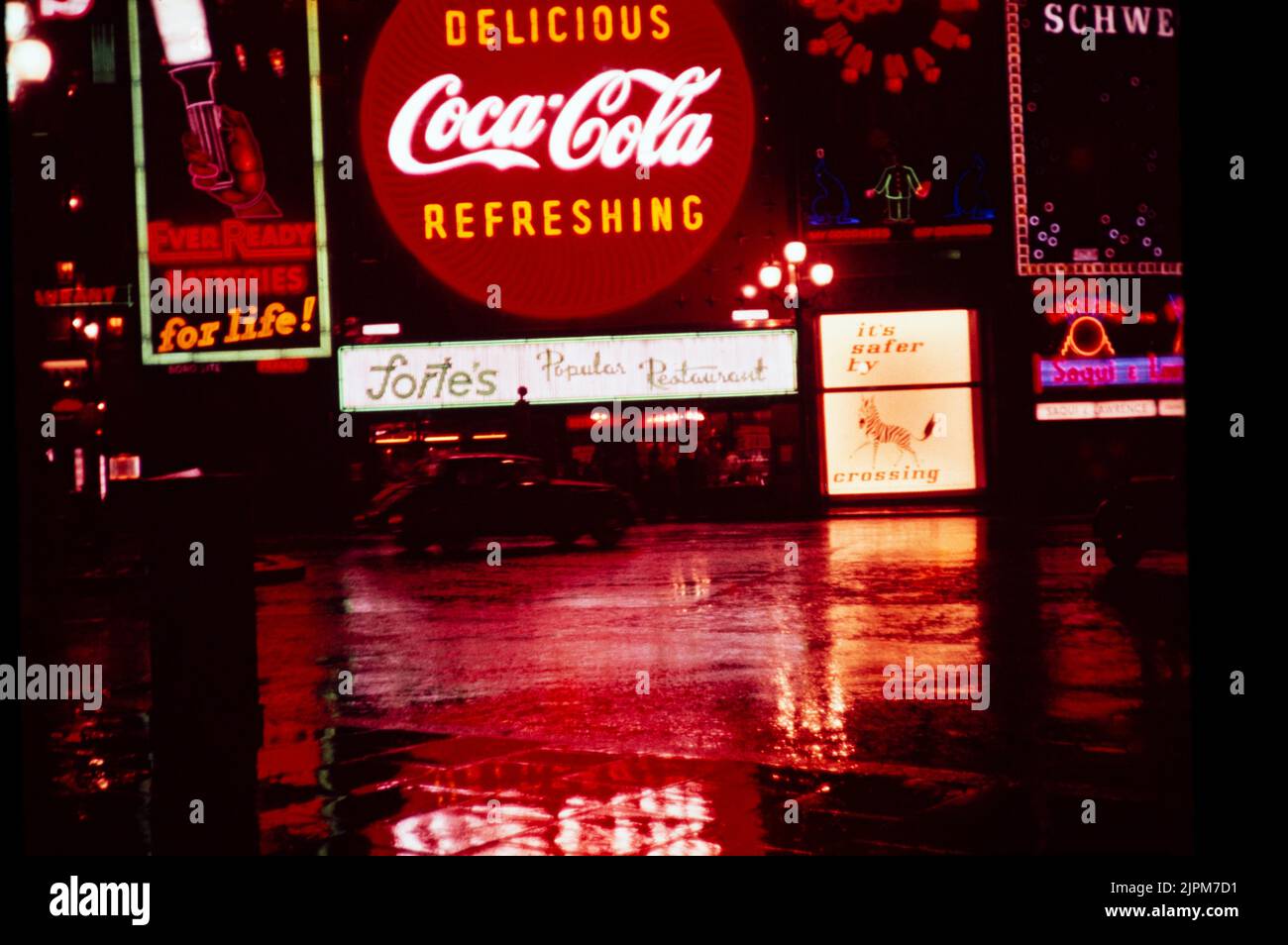 Neon-Werbeschilder bei Nacht Piccadilly Circus, London, England, Großbritannien 1957 - Coca Cola-Schild über dem Restaurant Fortes, Guinness-Uhr, ever Ready Batterien, Zebra Crossing Road Safety Promotion Kampagne Stockfoto