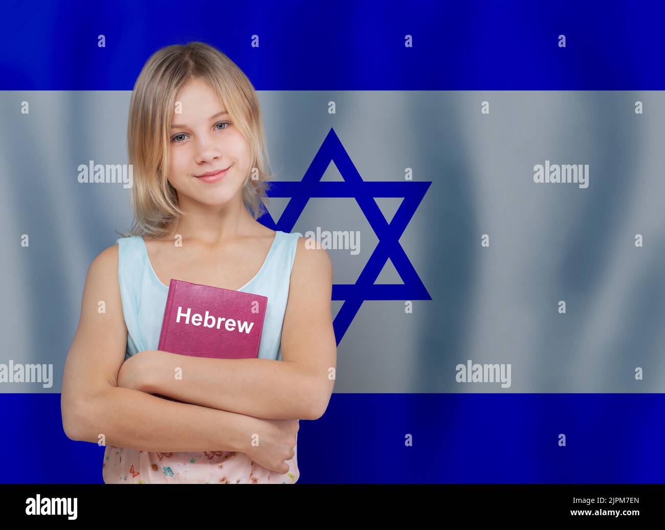 Nettes blondes Teenager-Mädchen umarmen Buch mit Aufschrift Hebräisch in hebräischer Sprache auf Flagge von Israel Hintergrund Stockfoto