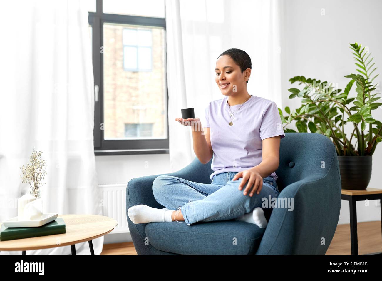 afroamerikanische Frau mit intelligentem Lautsprecher zu Hause Stockfoto
