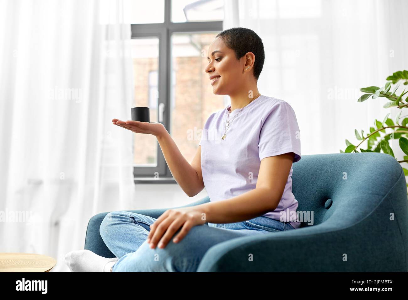 afroamerikanische Frau mit intelligentem Lautsprecher zu Hause Stockfoto