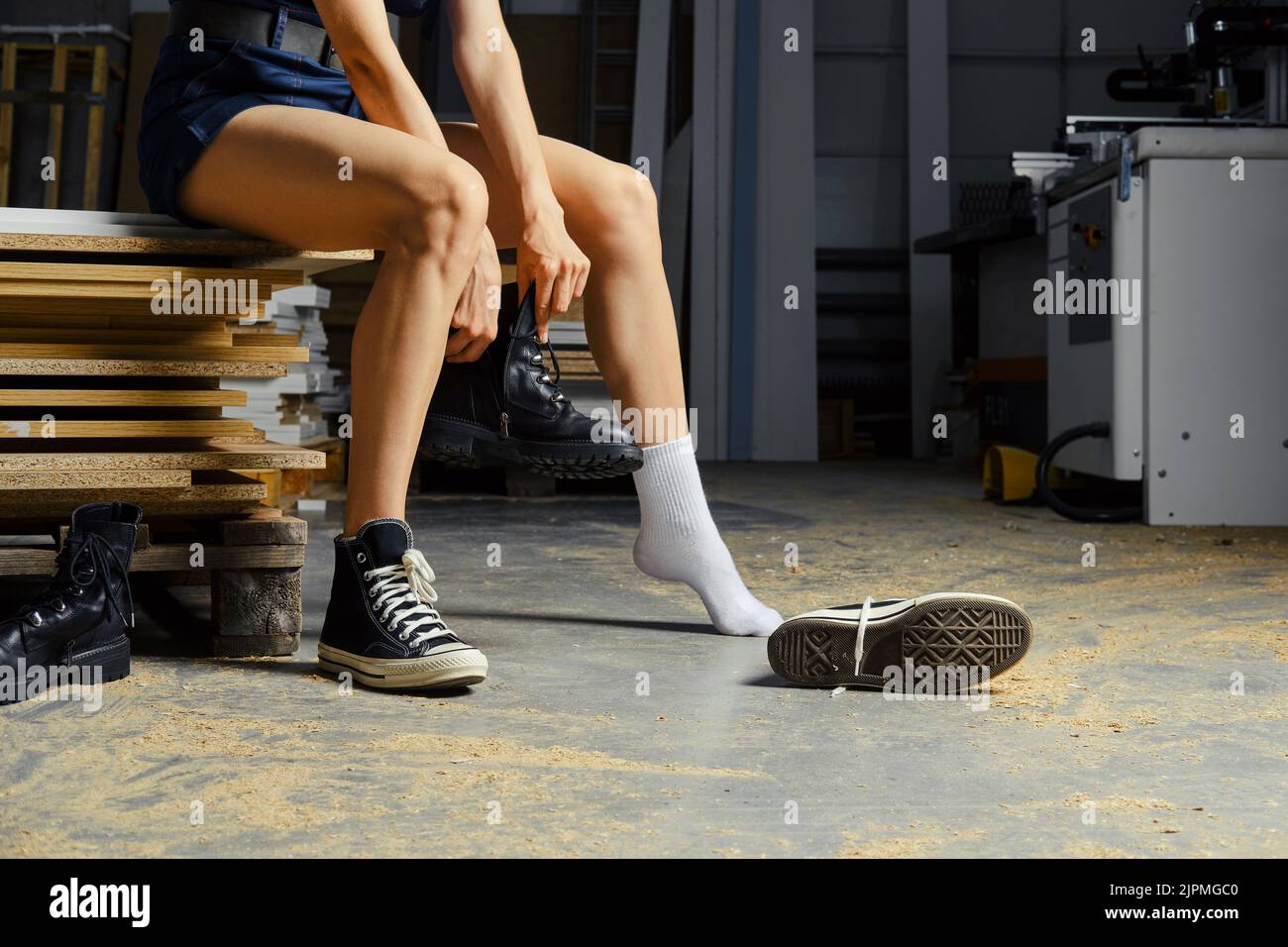 Weibliche Beine in der Tischlerei, Wechsel der Schuhe Stockfoto