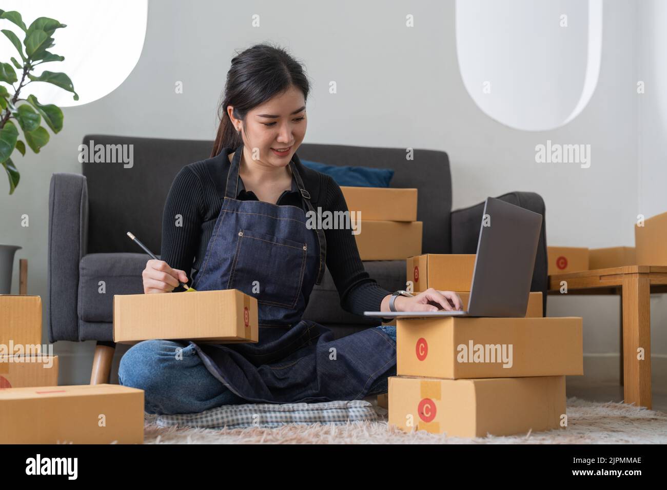 Startup Kleinunternehmen Eigentümer schriftlich Adresse auf Karton am Arbeitsplatz. Freelance Asian Frau Kleinunternehmen Unternehmer KMU arbeitet mit Box an Stockfoto