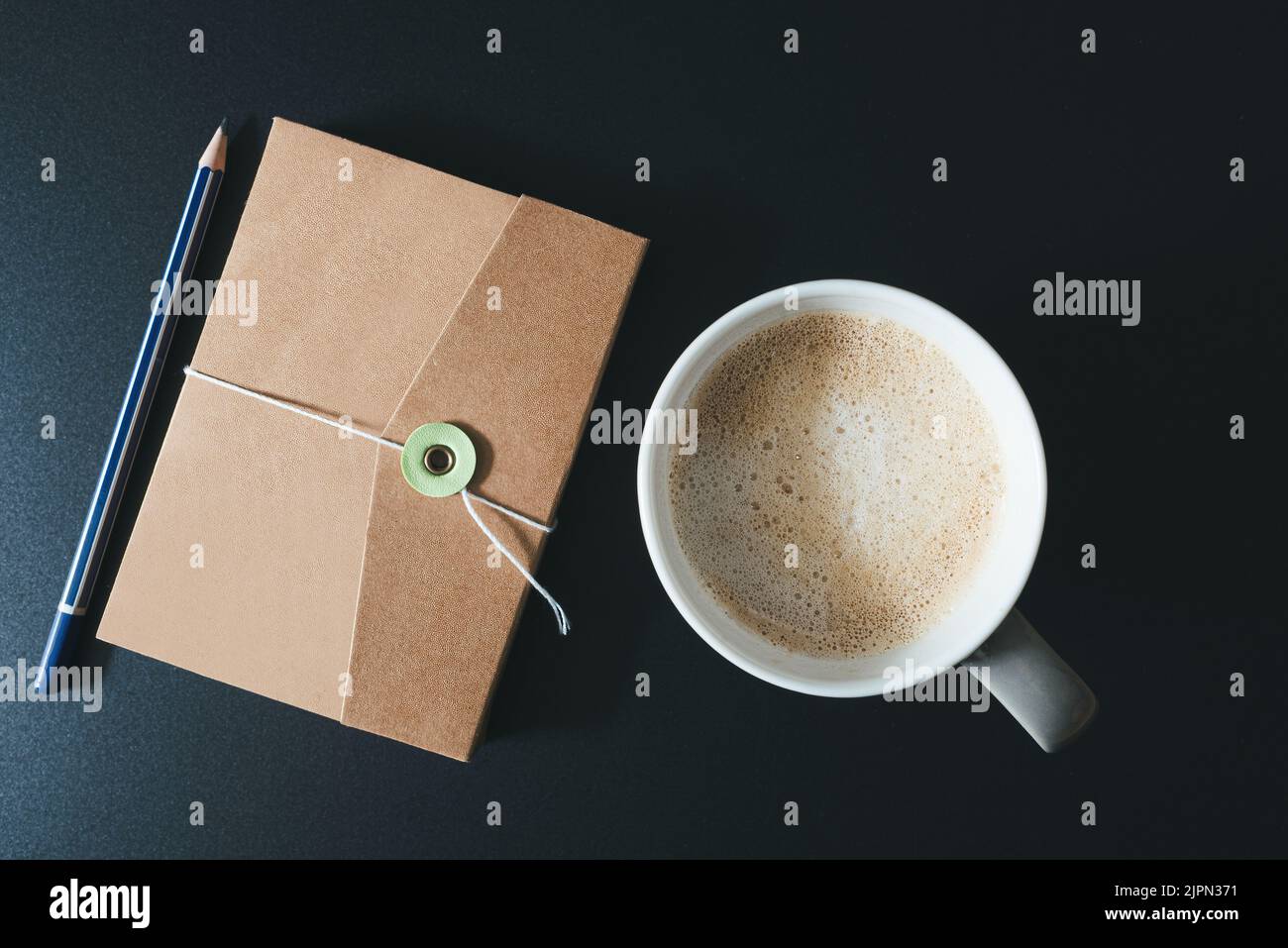 Draufsicht auf Tagebuch, Bleistift und Tasse Kaffee auf dunklem Tisch Stockfoto