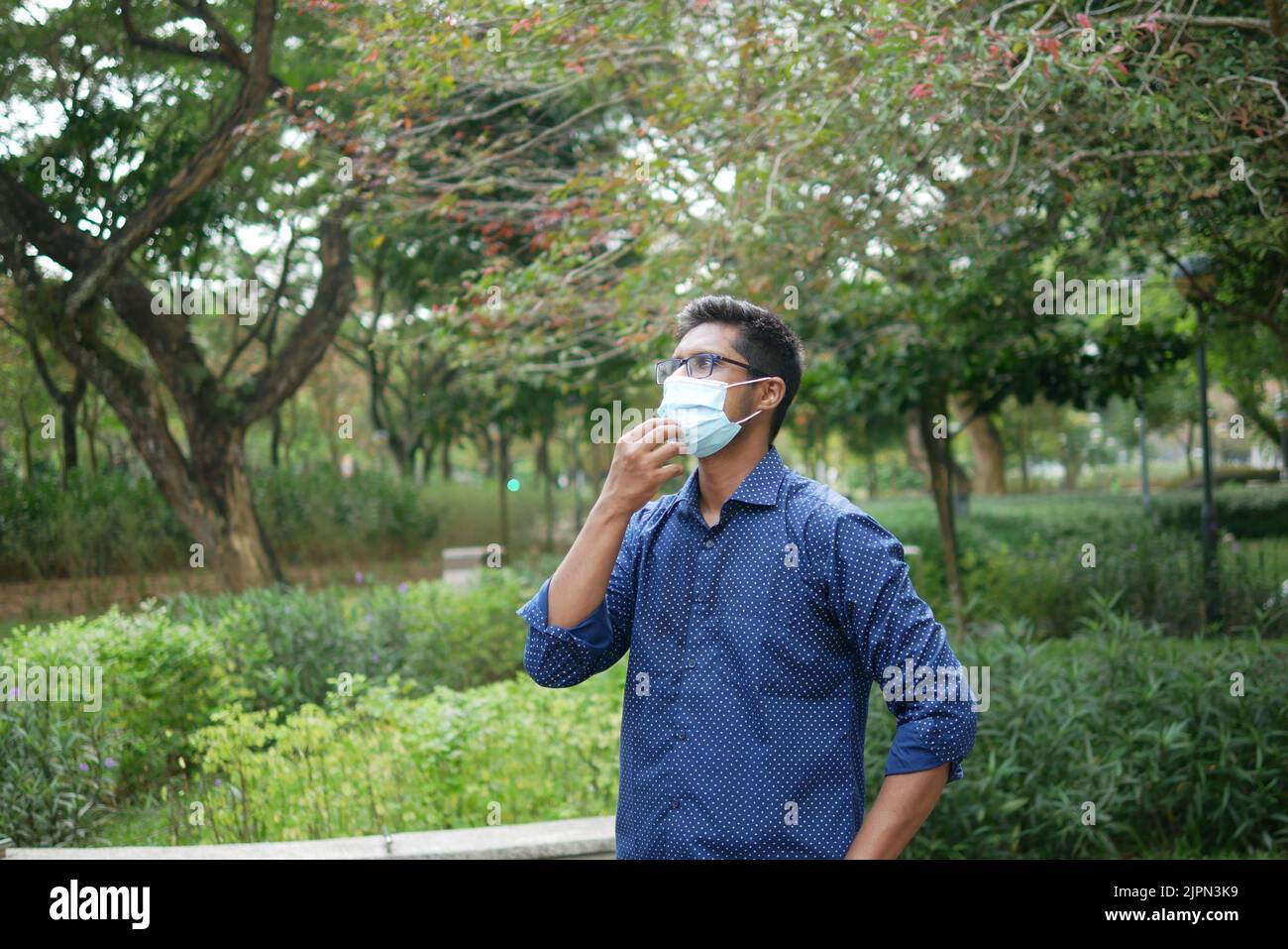 Junge asiatische Mann nimmt Maske aus im Freien Stockfoto