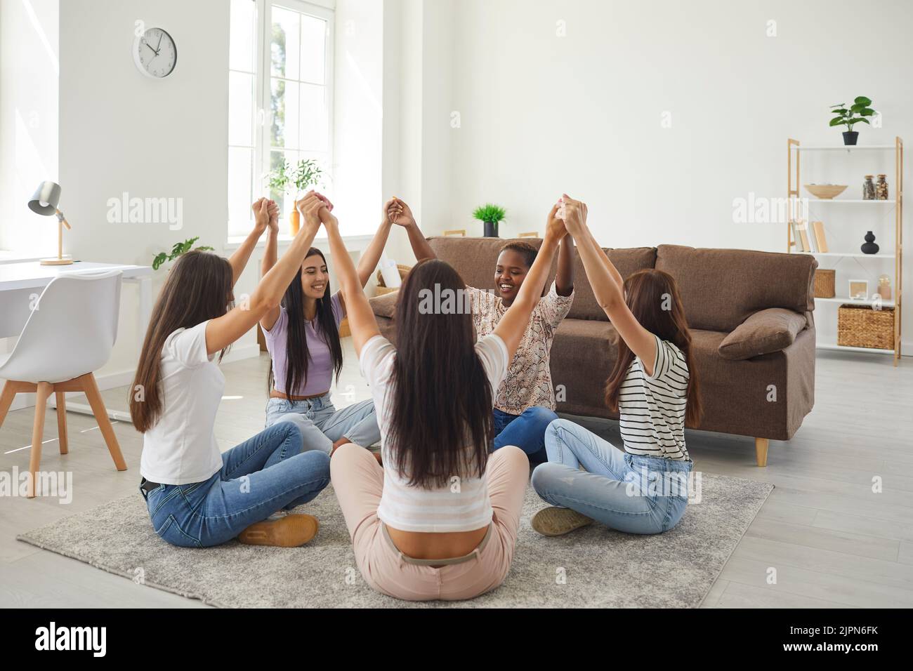 Glückliche multirassische Freundinnen bei der Begegnung zu Hause unterstützen sich gegenseitig und symbolisieren Einheit. Stockfoto