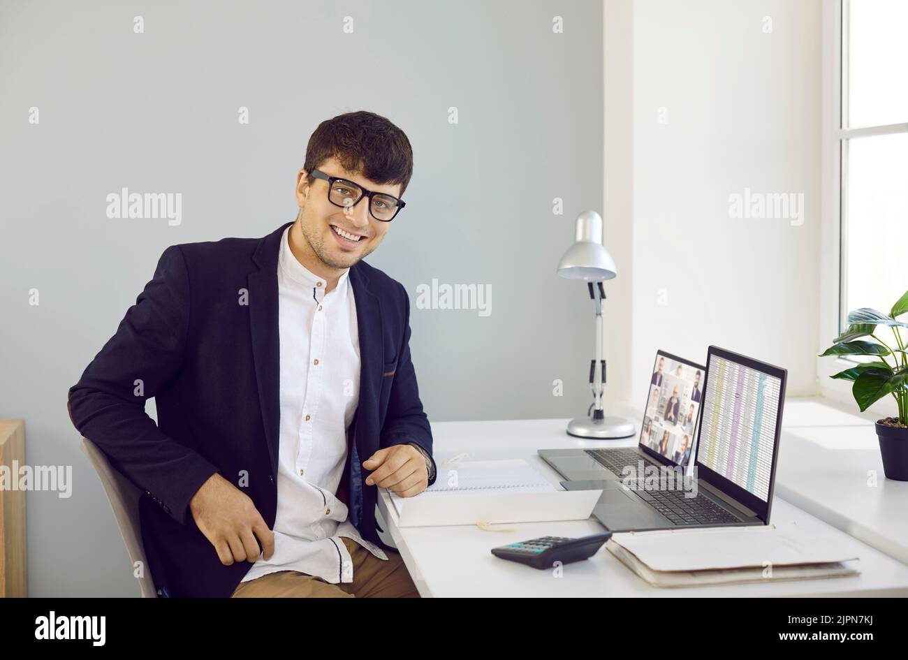 Porträt eines glücklichen jungen Geschäftsmannes oder Finanzbuchhalters bei der Arbeit im Büro Stockfoto