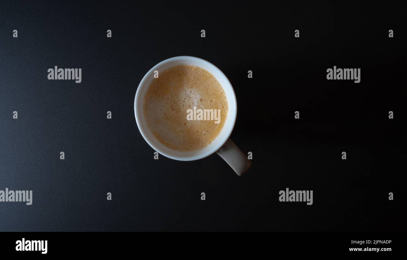 Draufsicht auf eine Tasse Kaffee oder Latte auf einem dunklen Tisch Stockfoto