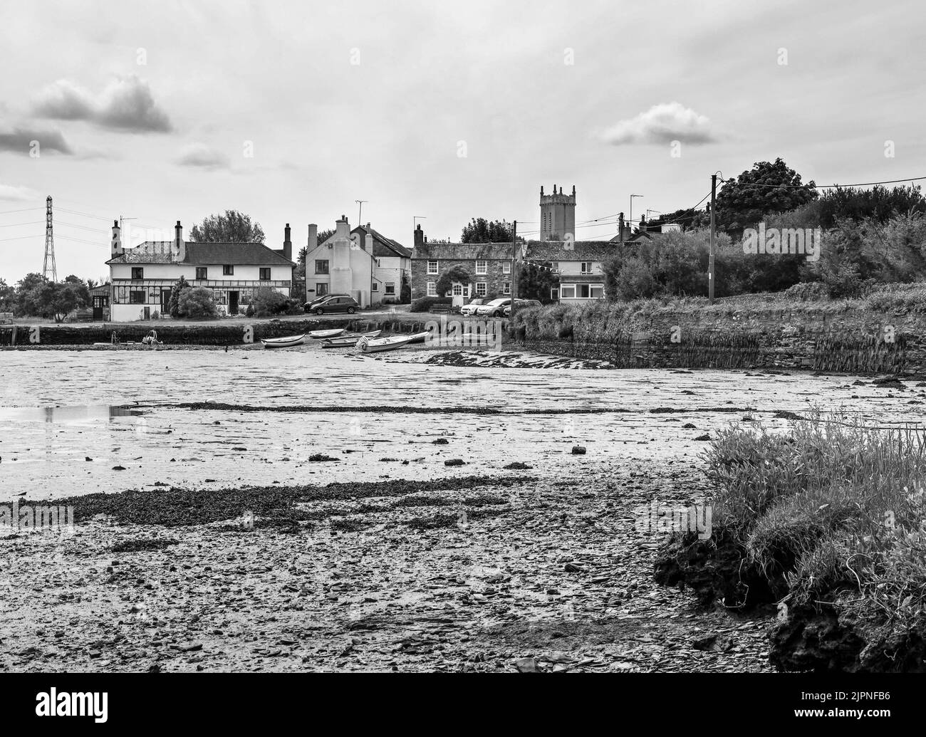 Krasses, schwarz-weißes Bild von Cottages am Quay, Bere Ferrers am Ufer des Flusses Tavy. Die Flut ist niedrig mit Mustern im Flussbett. Stockfoto