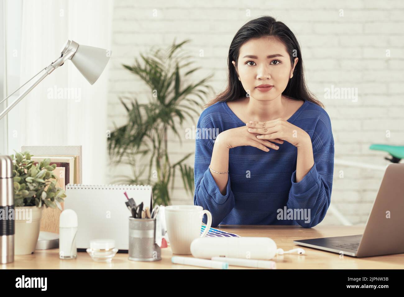 Porträt einer jungen asiatischen Unternehmerin an ihrem Tisch im Büro Stockfoto