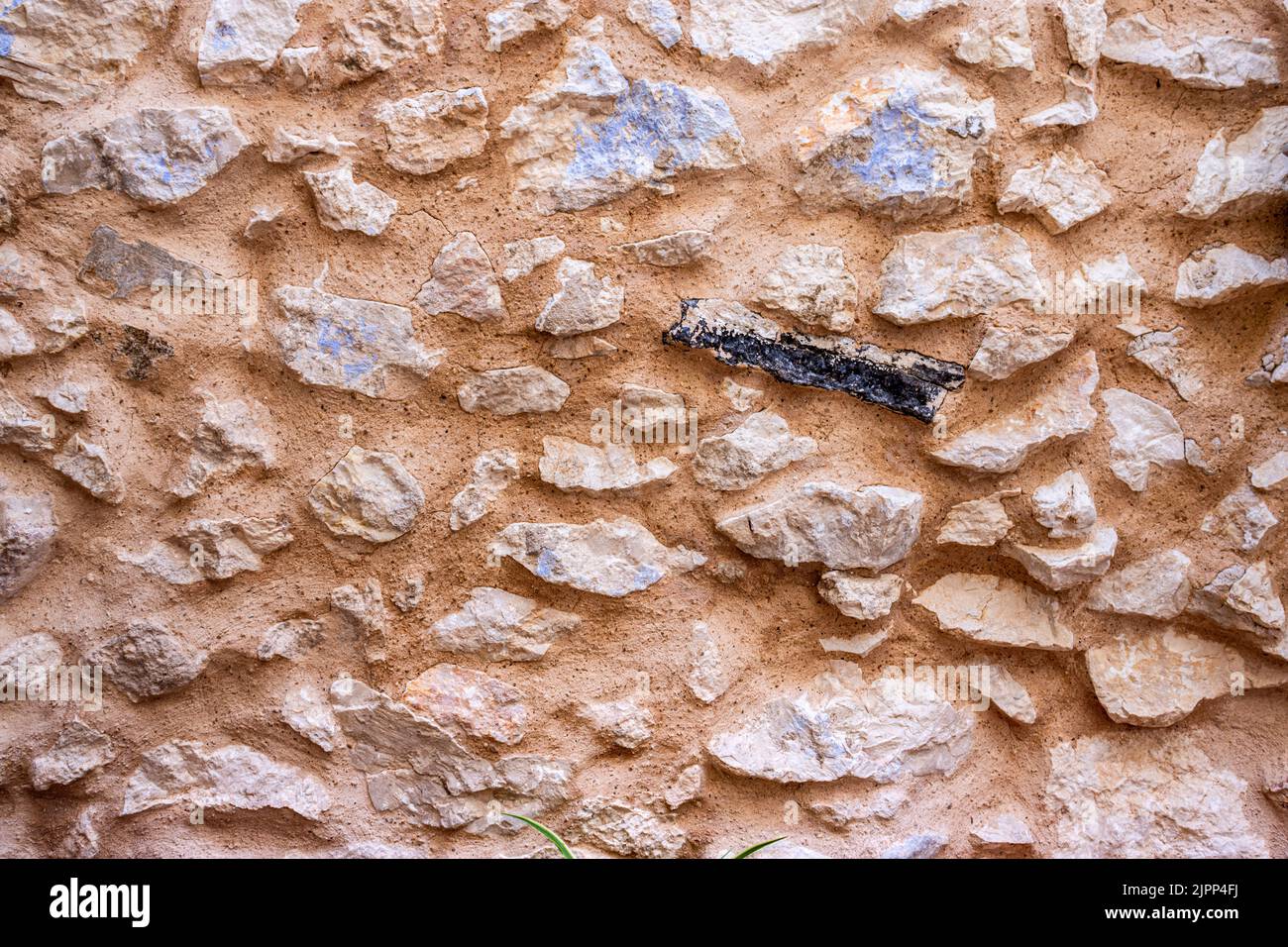 Natursteinmauer. Freiliegende Wand eines alten Hauses mit einem verkohlten Stück. Stockfoto