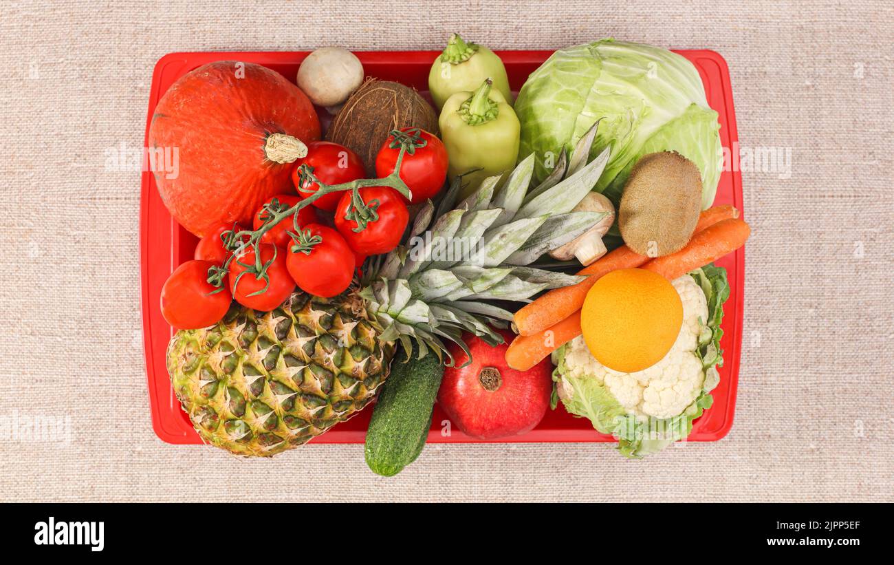 Rote Platte voll mit gesunden Lebensmitteln. Frisches Obst und Gemüse auf beigem Hintergrund. Flach liegend Stockfoto
