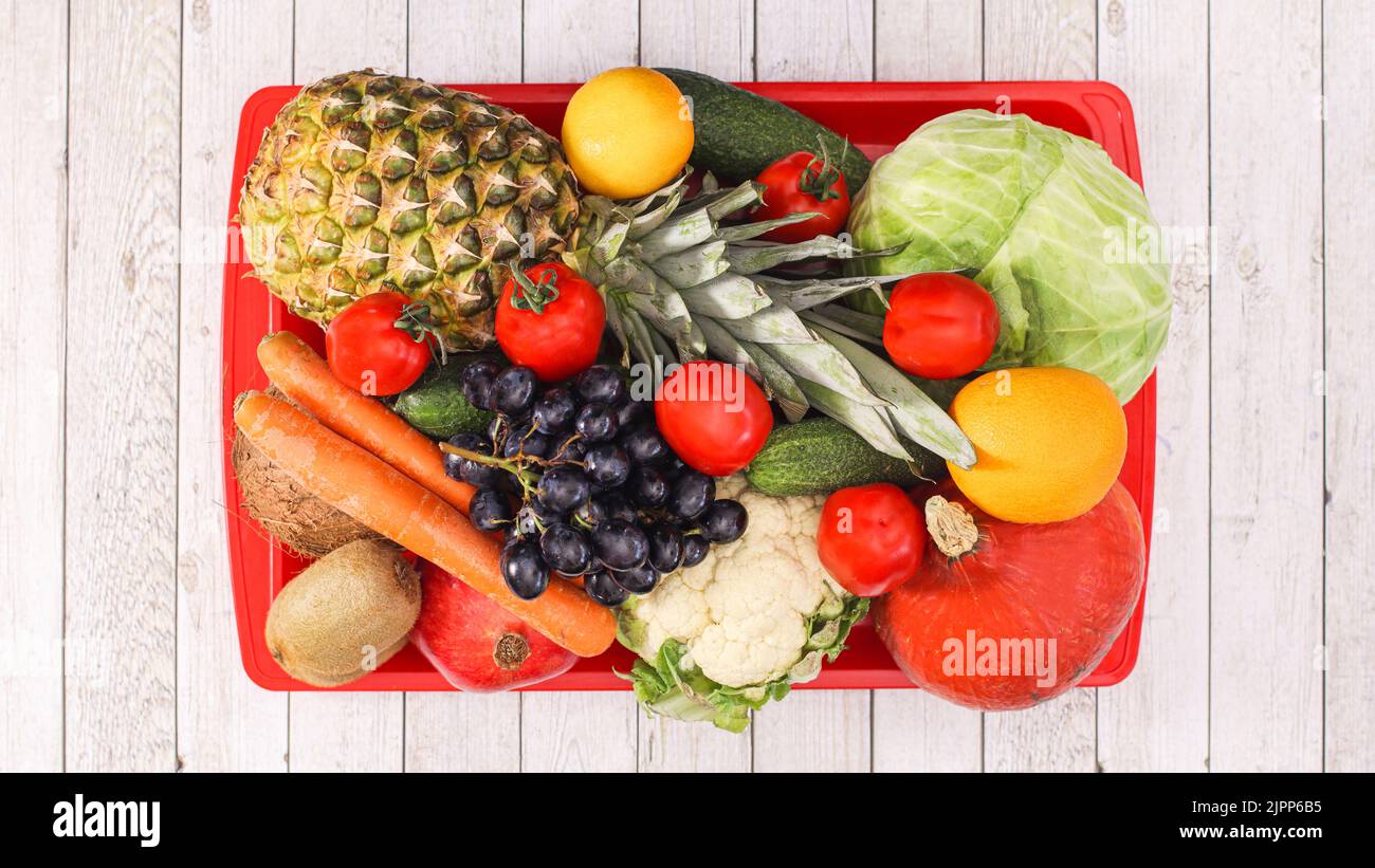 Rote Platte voll mit gesunden Lebensmitteln. Frisches Obst und Gemüse auf einem Holztisch. Flach liegend Stockfoto