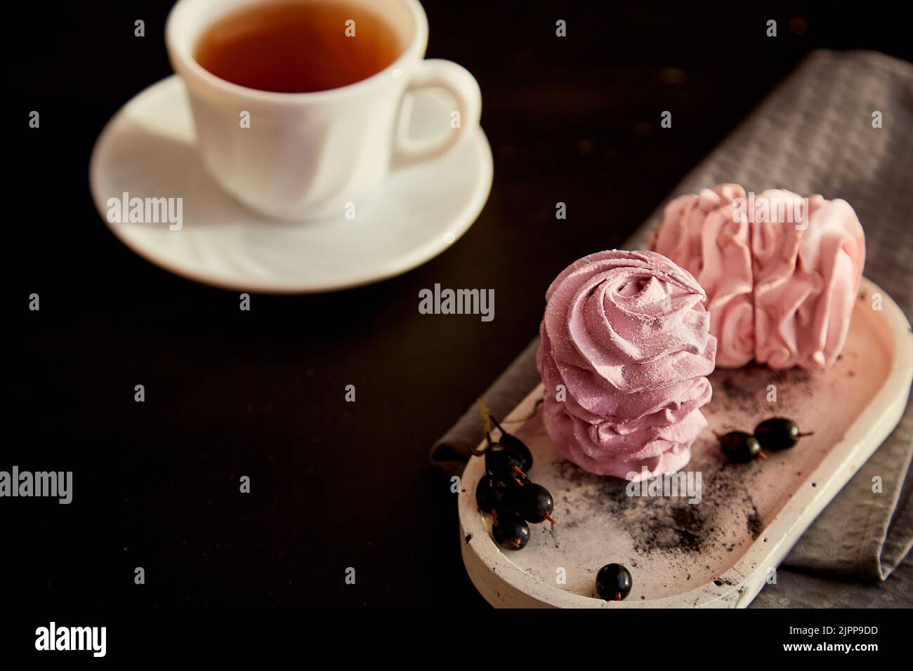 Ästhetisches Dessert - Beerenmarmelibe mit Johannisbeere und einer Tasse schwarzem Tee. Herbstlich gemütliche, stimmungsvolle Vorspeise. Gesunde Süßigkeiten, natürliche Lebensmittel Zucker und glutenfrei. Speicherplatz kopieren. Stockfoto