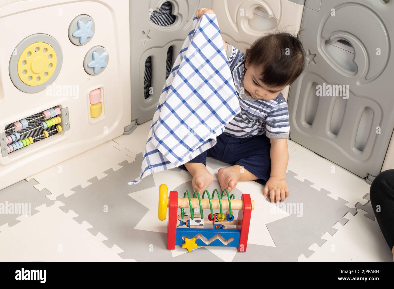 11 Monate alt Baby Junge zu Hause Hebetuch zu finden versteckte Spielzeug Piaget Objekt Dauerhaftigkeit Serie #2 Stockfoto