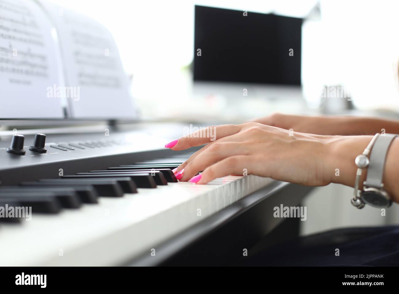 Weibliche Hand drückt die Tasten des Synthesizers und lernt zu spielen Stockfoto