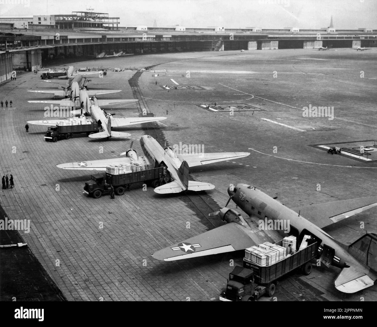 Während der Berliner Luftbrücke werden die Flugzeuge der US Navy Douglas R4D und der US Air Force C-47 am Flughafen Tempelhof entladen. Das erste Flugzeug ist eine C-47A-90-DL - 1948 Stockfoto