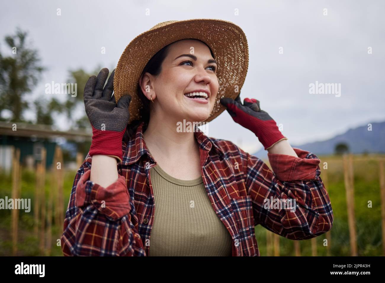 Glückliche Landwirtschaft Bäuerin Frau auf dem Bauernhof Überprüfung Wolken Himmel für Outdoor-Landwirtschaft, Gartenarbeit und Landleben. Nachhaltigkeitsmitarbeiter auf dem Rasen Stockfoto