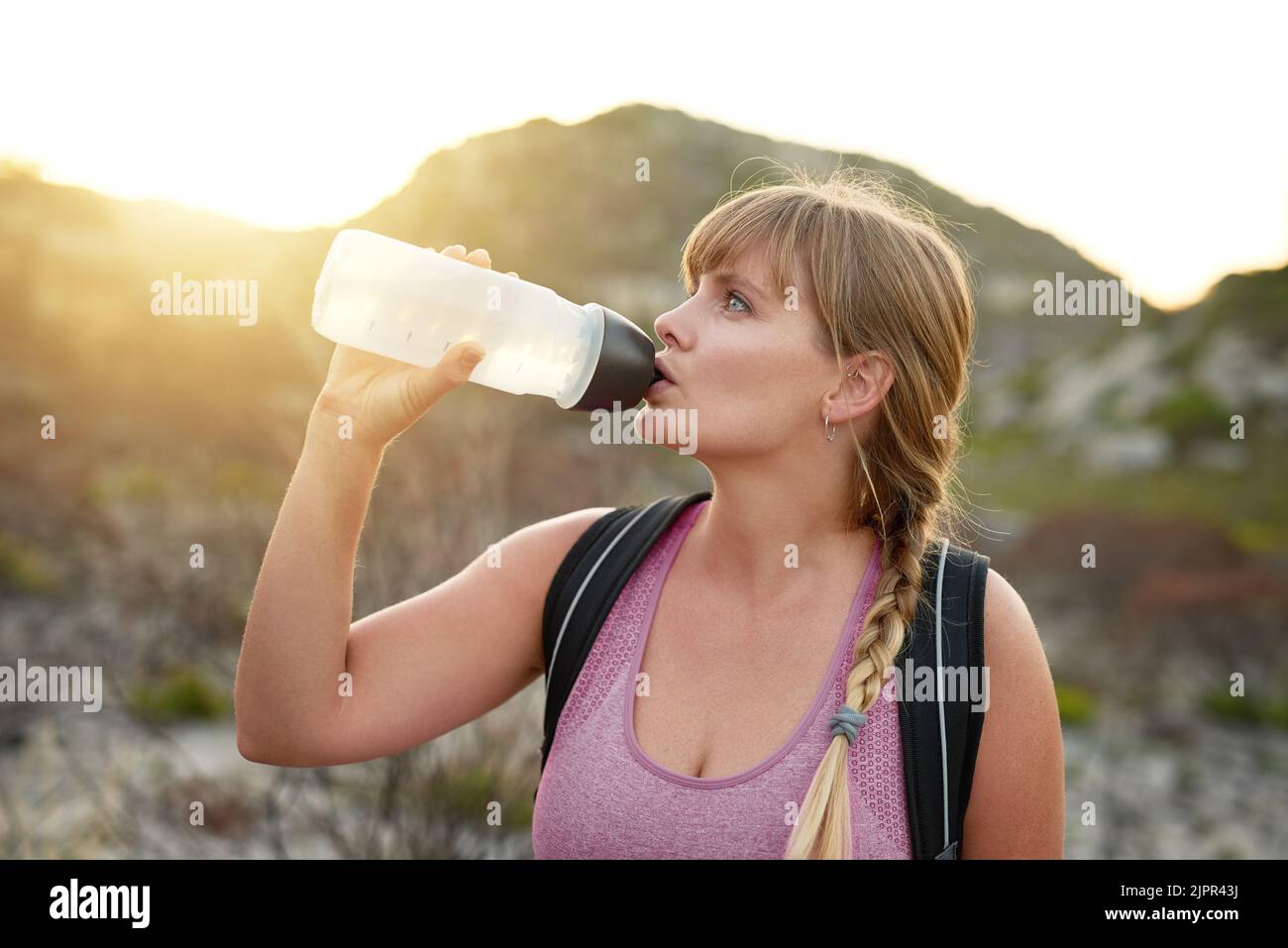 Eine attraktive junge Frau, die während einer Wanderung Wasser trinkt. Stockfoto