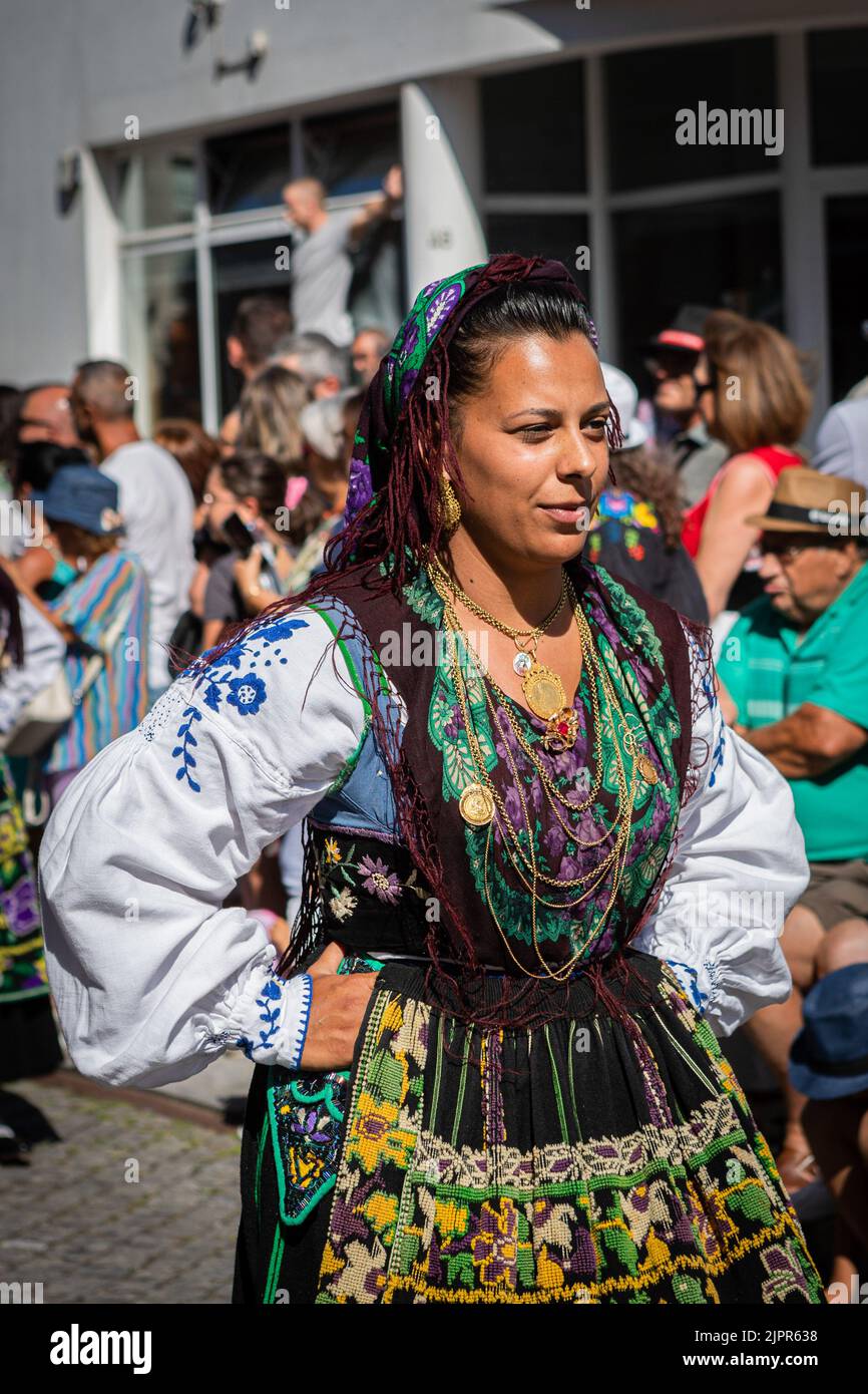 Porträt einer Frau, die die traditionelle Tracht in schwarz, grün und lila trägt. Mehr als eineinhalb tausend Frauen, die sich akribisch gekleidet haben, um die Geschichte der Wiener Frauen darzustellen, Stolz zogen sie entlang der Straßen der Stadt, um die schönen traditionellen Kostüme während der Mordomia Parade zu zeigen, die Teil der Romaria d'Agonia ist, die wegen der COVID-19 Pandemie zwei Jahre lang in der Warteschleife war. Tragen Sie die schönen Folklore-Kostüme aus den verschiedenen Dörfern, die Teil der Gegend von Viana do Castelo sind, mit großen Mengen an Gold um den Hals, viele Gegenstände tatsächlich Erbstücke aus dem Centu Stockfoto