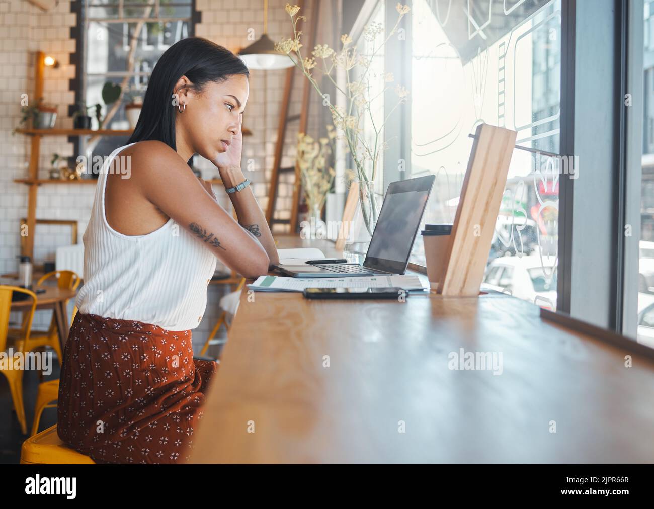 Gestresste, denkende und arbeitende Frau auf einem Laptop in einem Café, beim Ansehen eines Videos oder beim Empfangen schlechter Nachrichten bei einem Videoanruf. Seriöse Schüler, die an einem studieren Stockfoto