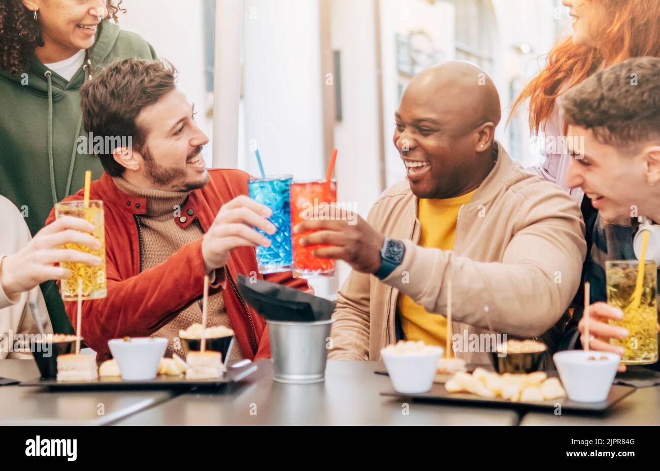 Happy Multiracial Friends Group Toast, Drink and Eating at Restaurant Meeting - Life Style Konzept mit Hipster-Freunden teilen sich Happy Hour Zeit zusammen Stockfoto