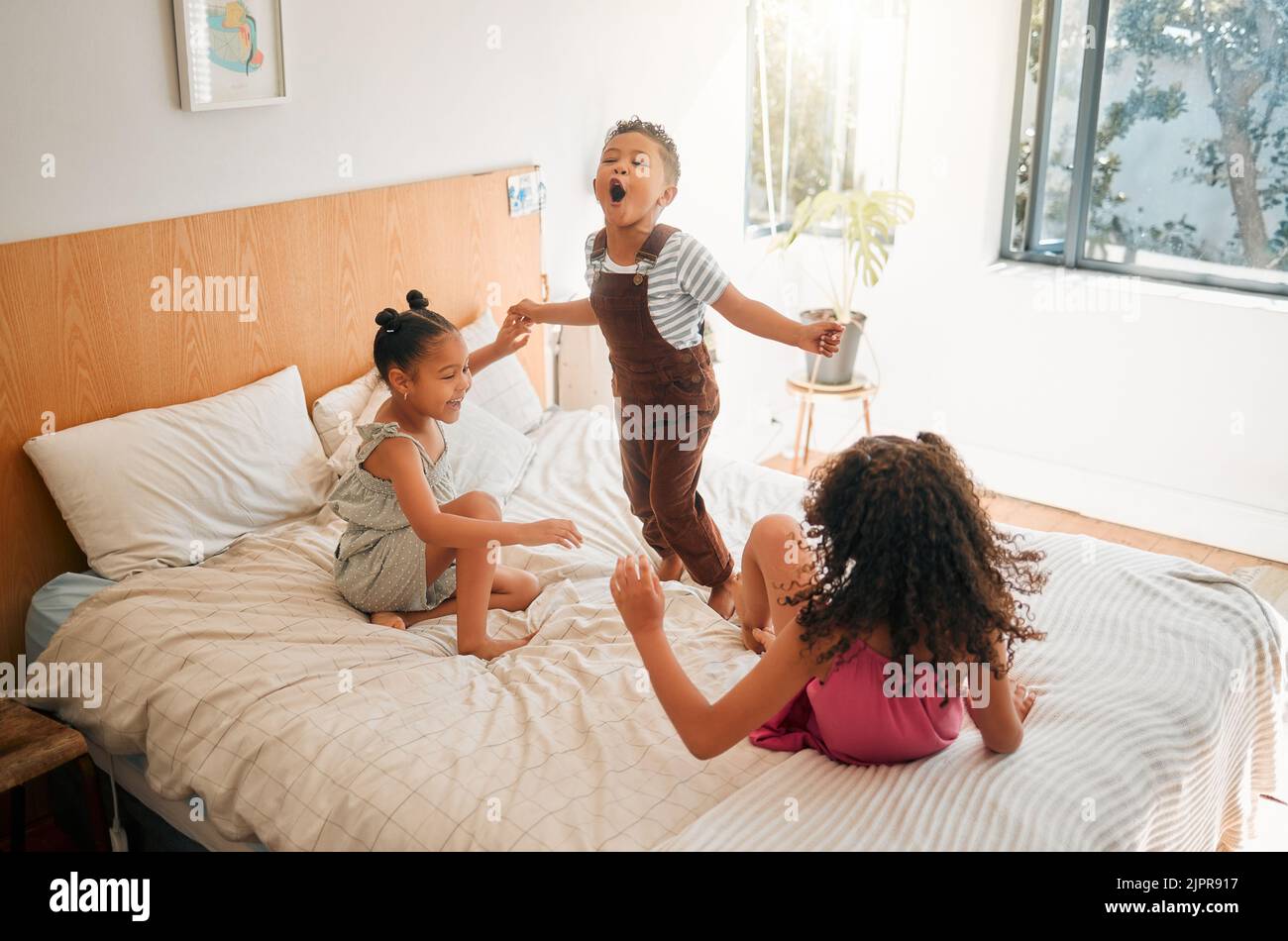 Kinder, Spaß und Energie durch das Spielen Geschwister springen, verbinden und genießen ein Spiel auf dem Bett zu Hause zusammen. Kinder lachen und Spaß haben, teilen Stockfoto