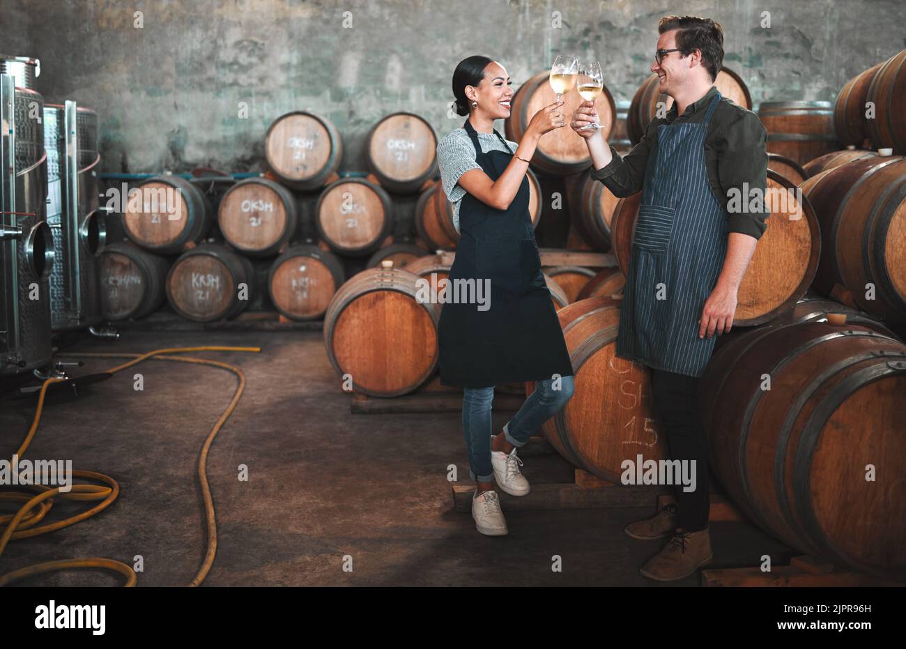 Weinbrennereibesitzer feuern Gläser im Keller an, die neben den Fässern stehen. Glückliche und feiernden Unternehmer oder Sommeliers genießen chardonnay Stockfoto