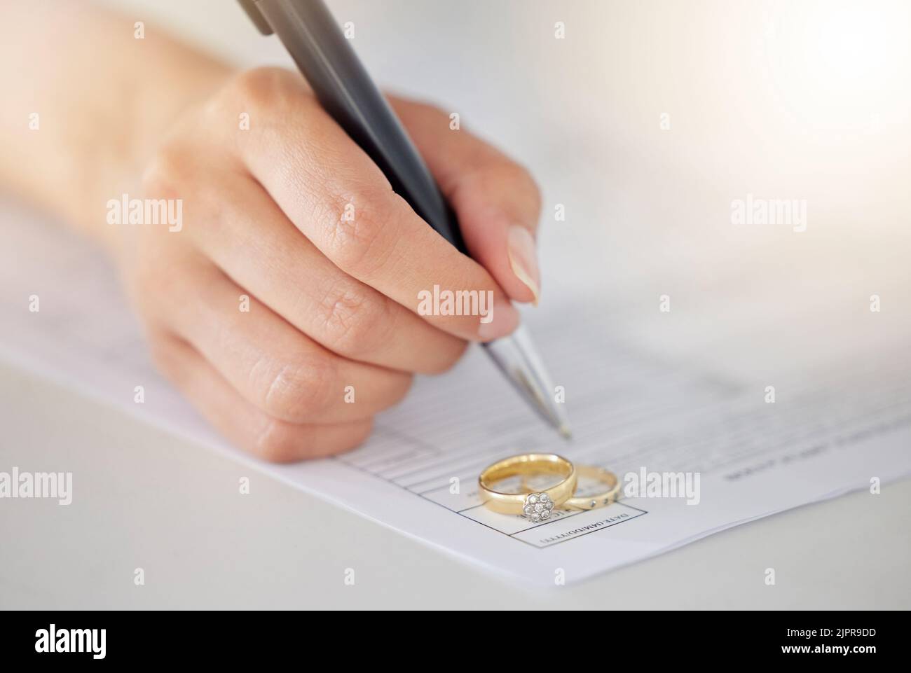 .Woman Hand Unterzeichnung von Scheidungsdokumenten, Deal oder Papiervertrag in einem Anwaltsbüro mit Ring auf dem Tisch platziert. Person, die die Unterschrift auf der Ehe schreibt Stockfoto