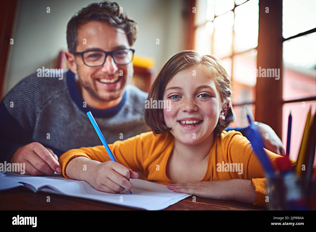 Wir lernen viel voneinander. Porträt eines Vaters, der seiner kleinen Tochter bei ihren Hausaufgaben hilft. Stockfoto