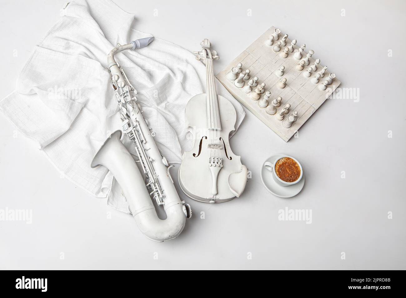 Saxophon, Violine, Schach und Tasse Kaffee auf weißem Hintergrund Stockfoto