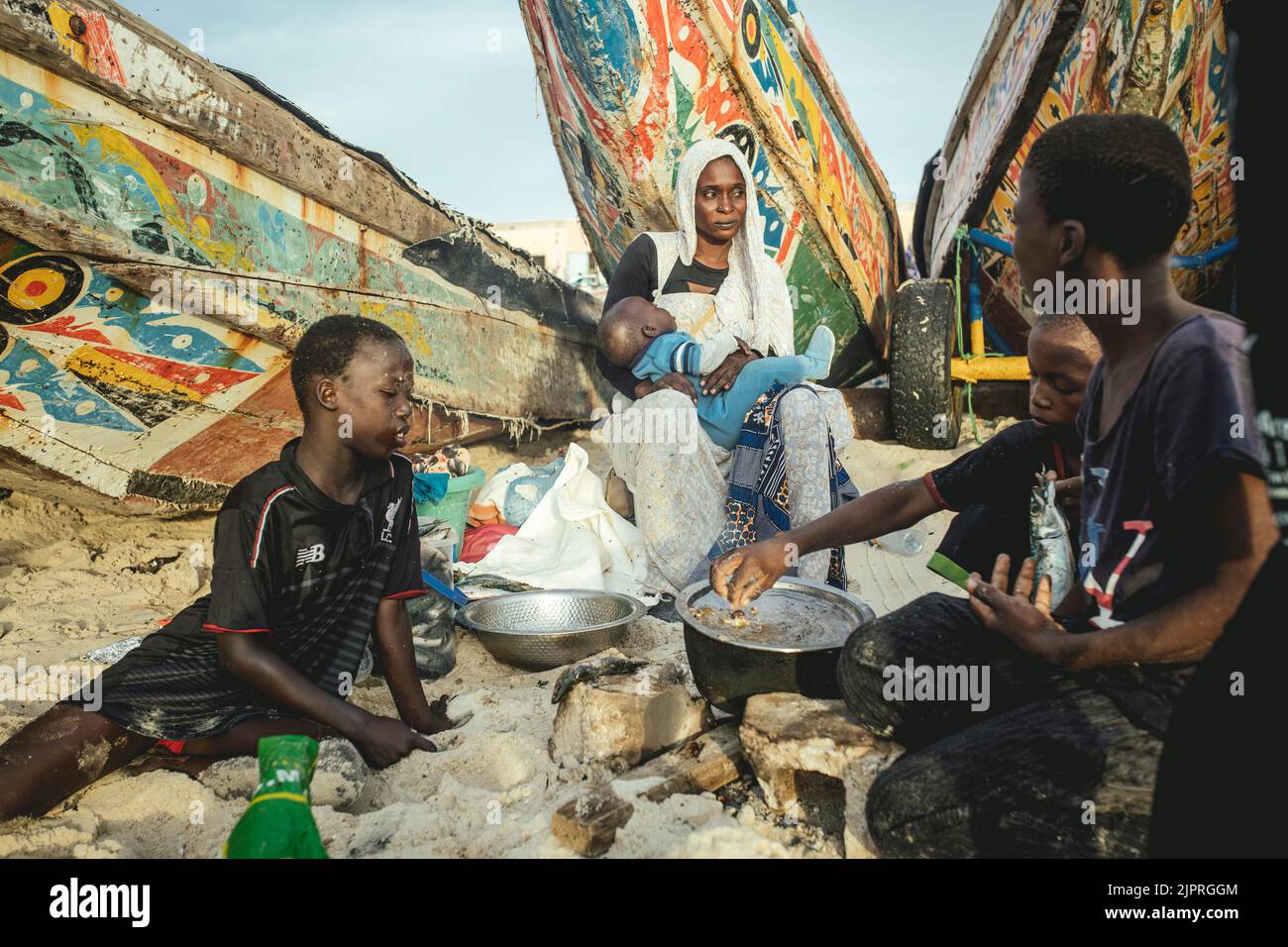 Traditioneller Fischerstrand, Plage des Pecheurs Traditionnels, eine Familie, die unter ihrem Boot Nouakchott, Mauretanien, Sardinen fischt Stockfoto