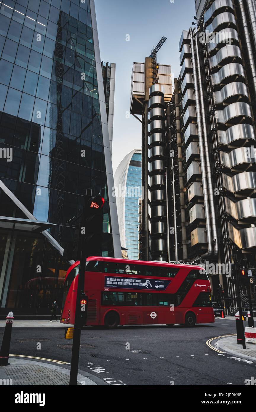 Eine Nahaufnahme eines roten Busses, der in der Nähe des Fenchurch Building hinter Lloyd's of London fährt Stockfoto