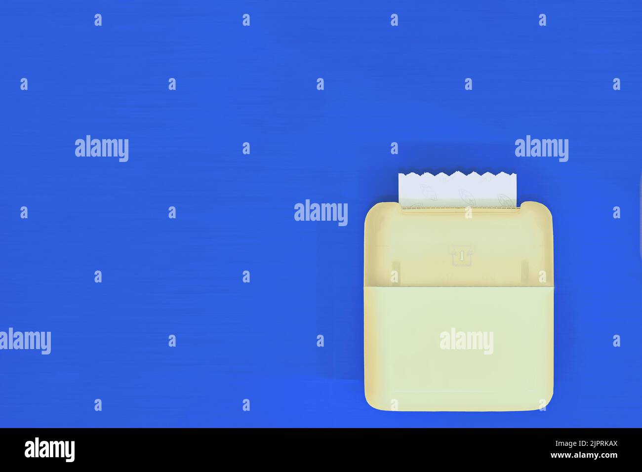 Gelber Toilettenpapierhalter an blauer Wand Stockfoto