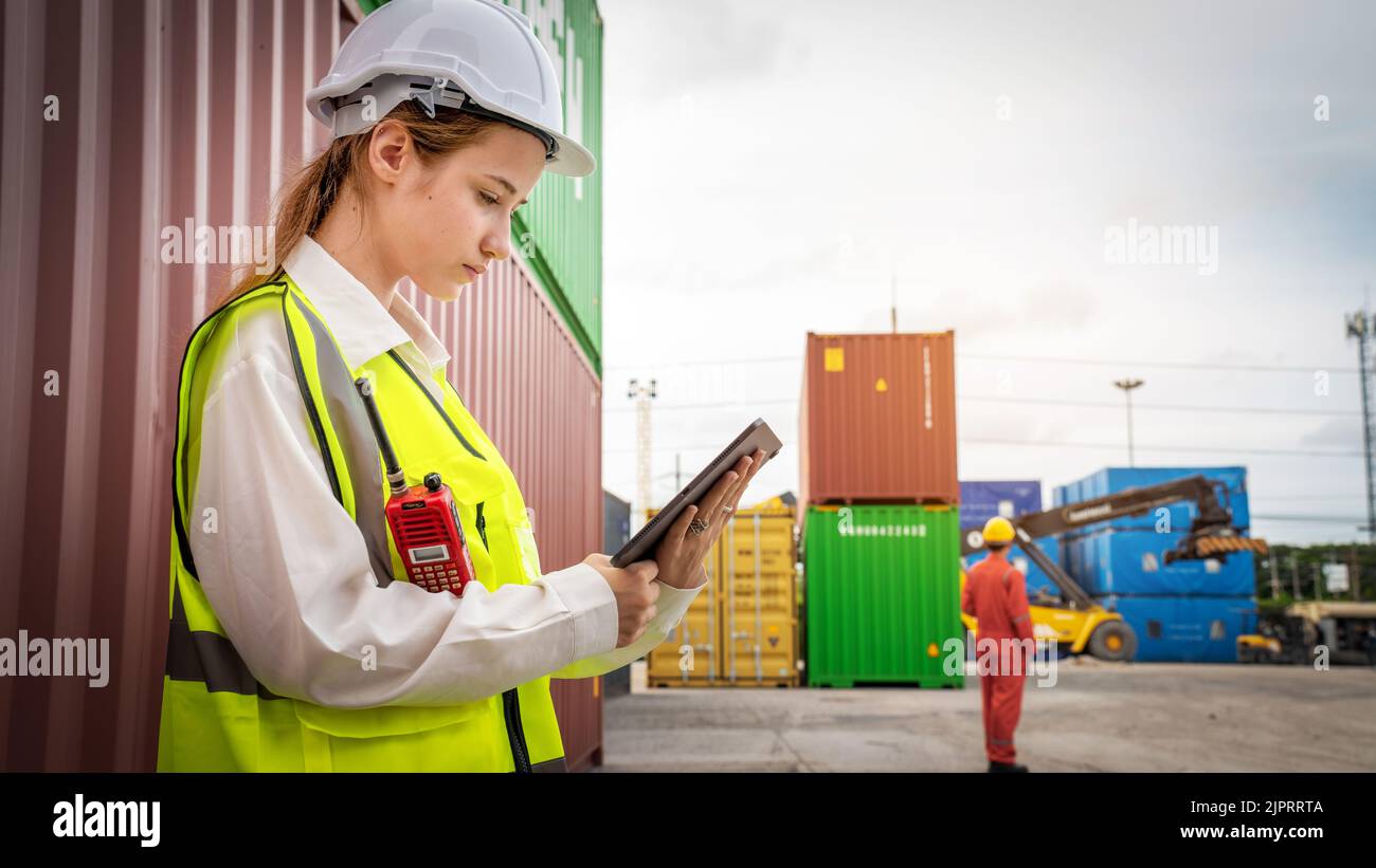 Frau Vorarbeiter lächeln an der Seite des Gabelstaplers im Lager, Manager verwenden Tablet in weißem Helm Safety Supervisor in Container Custom Terminal Port CO Stockfoto