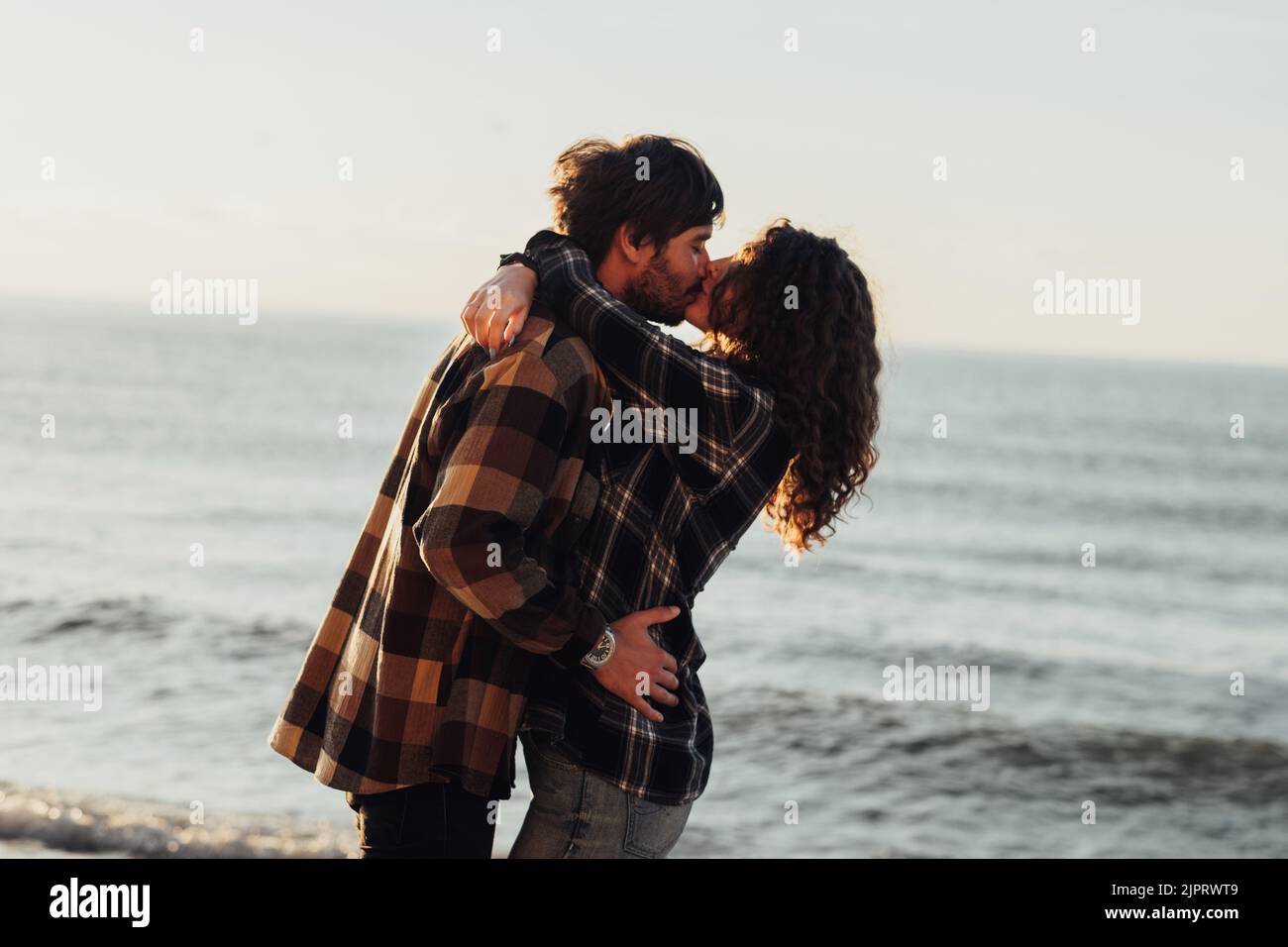 Frau und Mann umarmen und küssen mit Meer auf dem Hintergrund, junge Paar verlieben sich Stockfoto