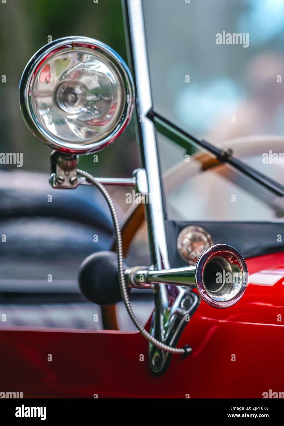 Glänzendes Stahlhorn auf rotem Oldtimer, Nahaufnahme Detail, nur Metallfelge im Fokus Stockfoto