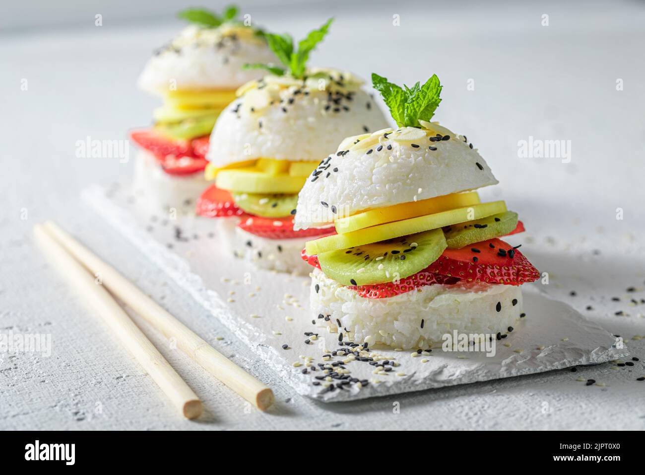 Frischer und köstlicher Sushi-Burger mit Erdbeeren und Mascarpone als japanisches Dessert. Sushi mit Früchten, die auf einzigartige Weise zubereitet werden. Stockfoto