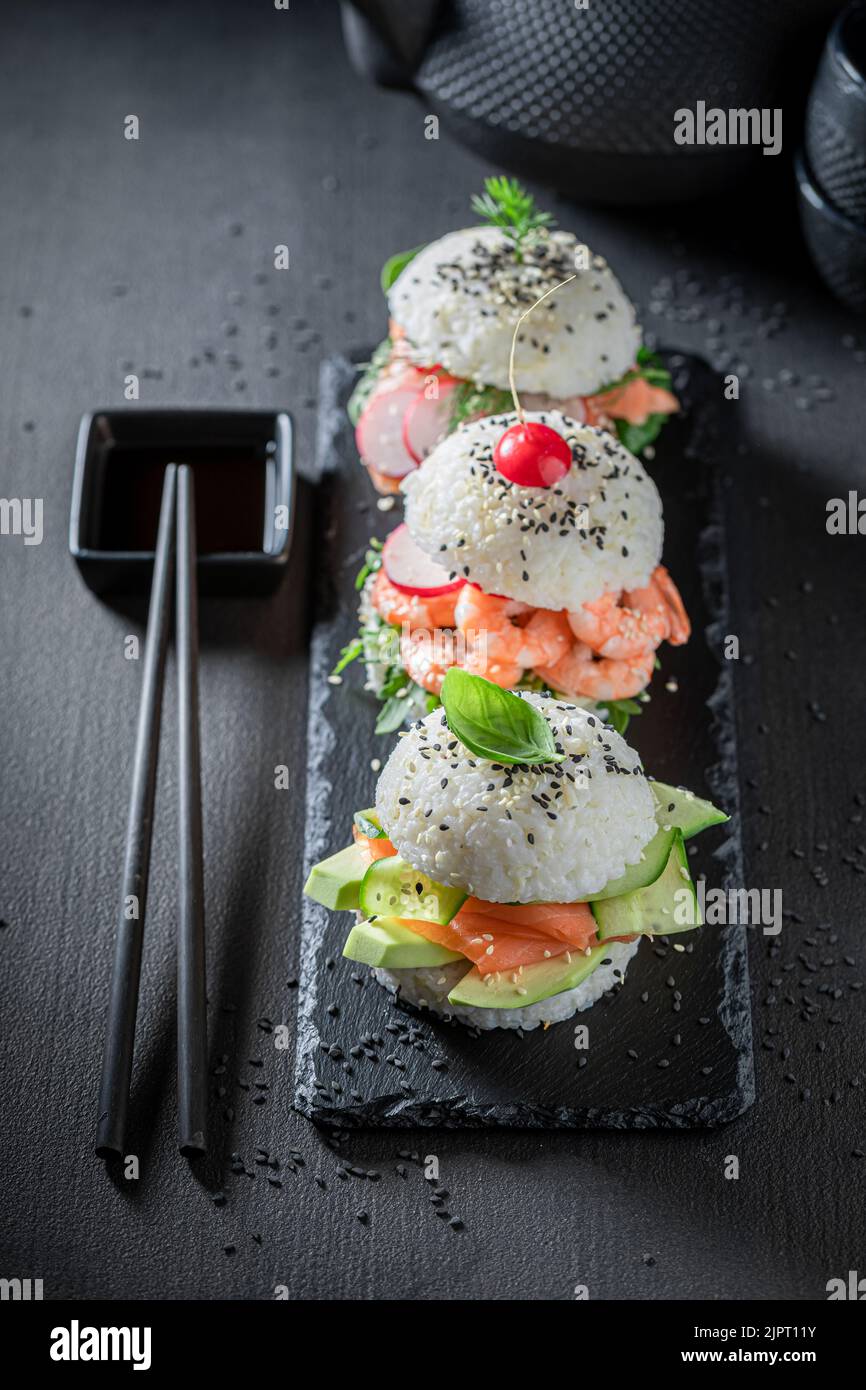 Gesunder und schmackhafter Sushi-Burger mit Avocado und Lachs als japanische Vorspeisen. Sushi mit Meeresfrüchten, die auf einzigartige Weise zubereitet werden. Stockfoto