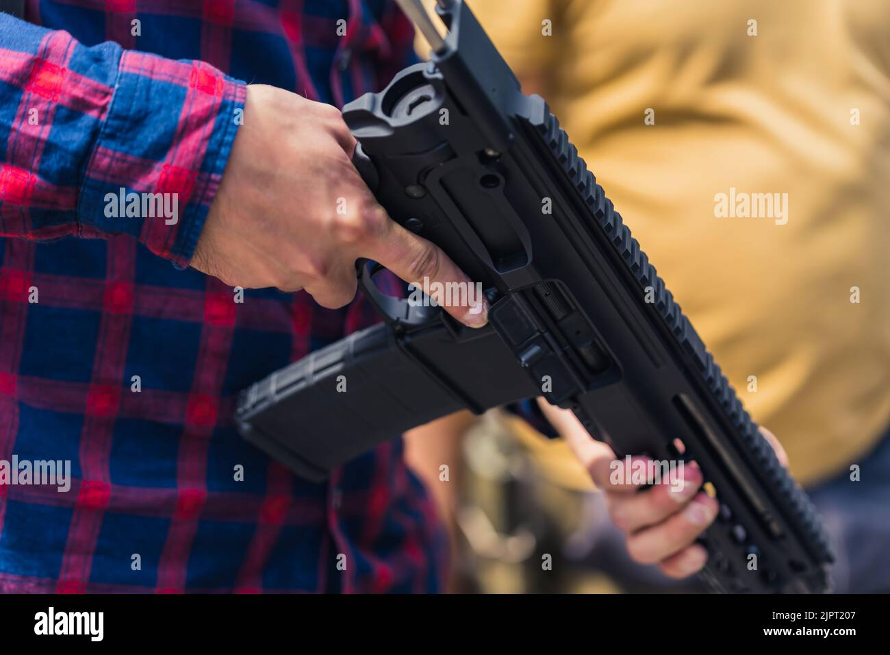 Nahaufnahme der Arme des Mannes mit Uzi-Waffe. Schusswaffentraining. Horizontale Außenaufnahme. Hochwertige Fotos Stockfoto