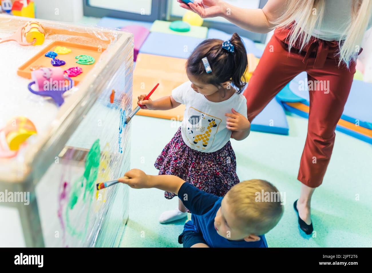 Niedliche kleine Kinder malen mit Bürsten im Kindergarten. Hochwertige Fotos Stockfoto